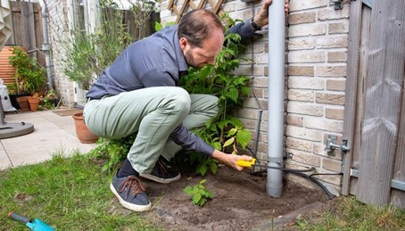 Koppel de regenpijp van het riool en sluit hem aan op een regenton of een waterzak