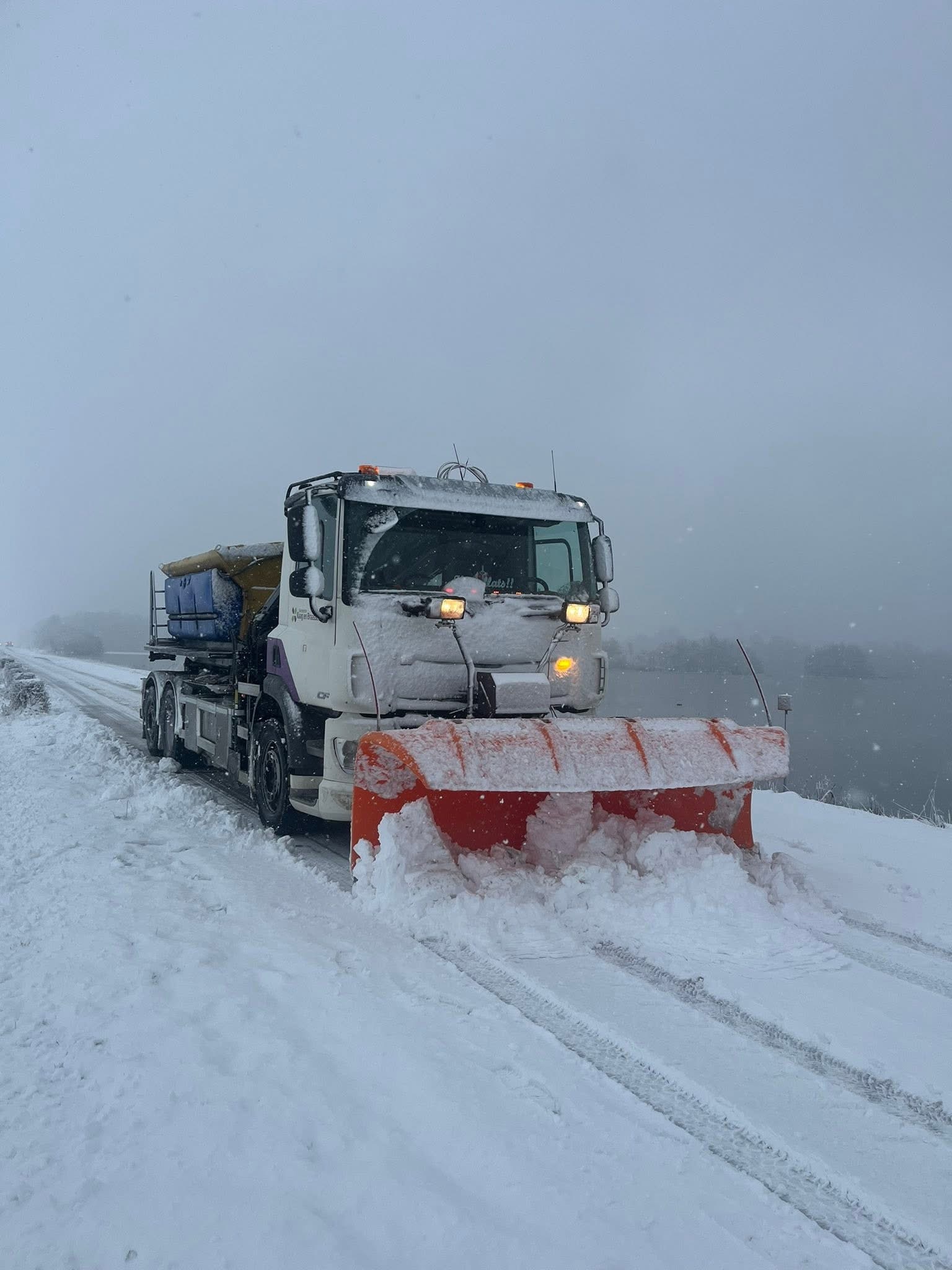 Foto van een strooiwagen in de sneeuw