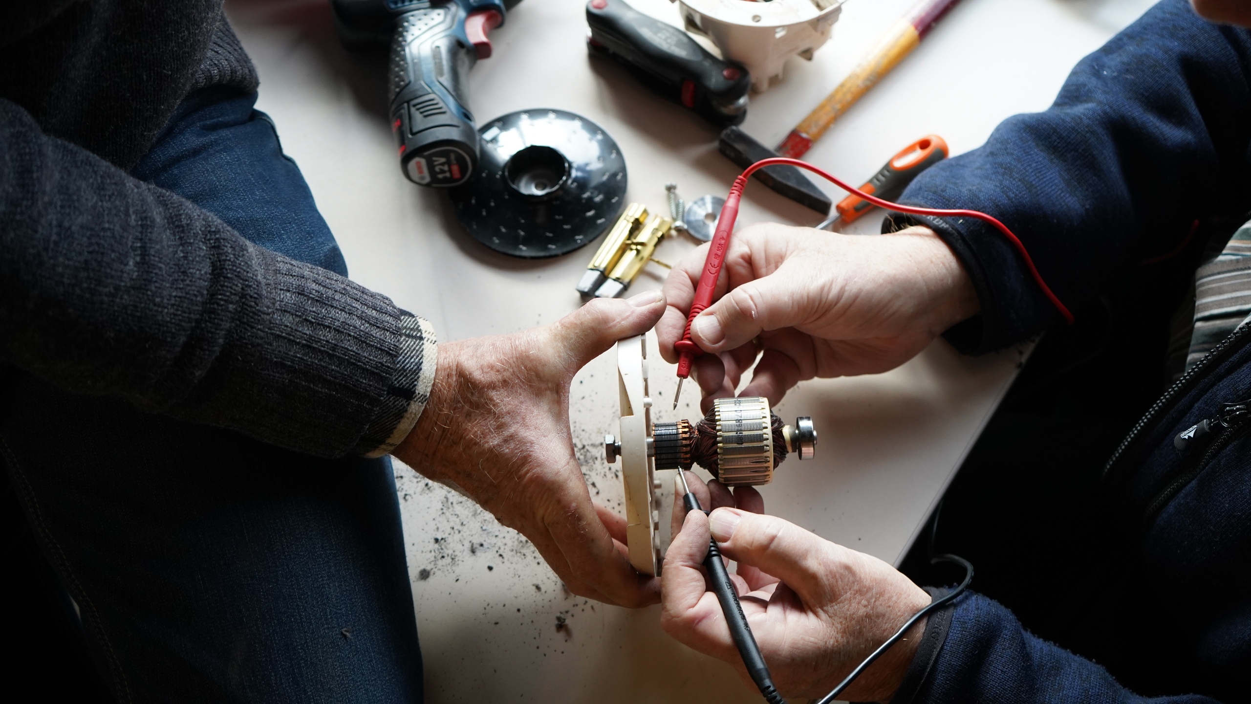 sfeerafbeelding van twee personen die samen een elektrisch apparaat repareren.
