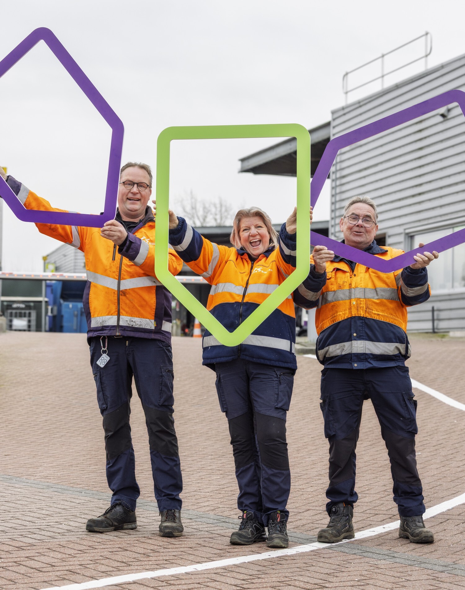Collega's van de buitendienst met gekleurde huisvormige frames bij de milieustraat